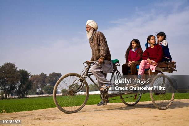 An village elder, grandfather to one of the children takes the girls for a rickshaw ride in the surrounding region to their village, Chita Kalaan,...