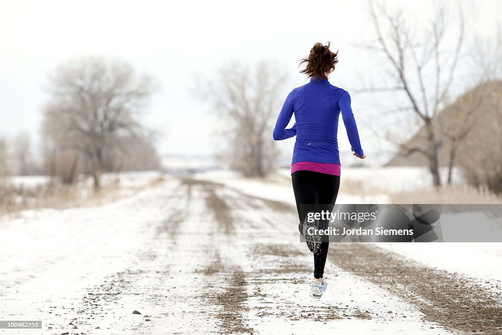 An Athletic woman jogging in the winter.