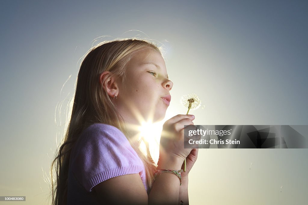 Girl blowing on a dandelion