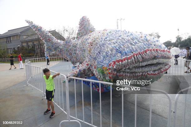 Boy poses with a 9.1-metre-long whale made of 40,000 abandoned plastic bottles for a photo at Rizhao Ocean Park on July 21, 2018 in Rizhao, Shandong...