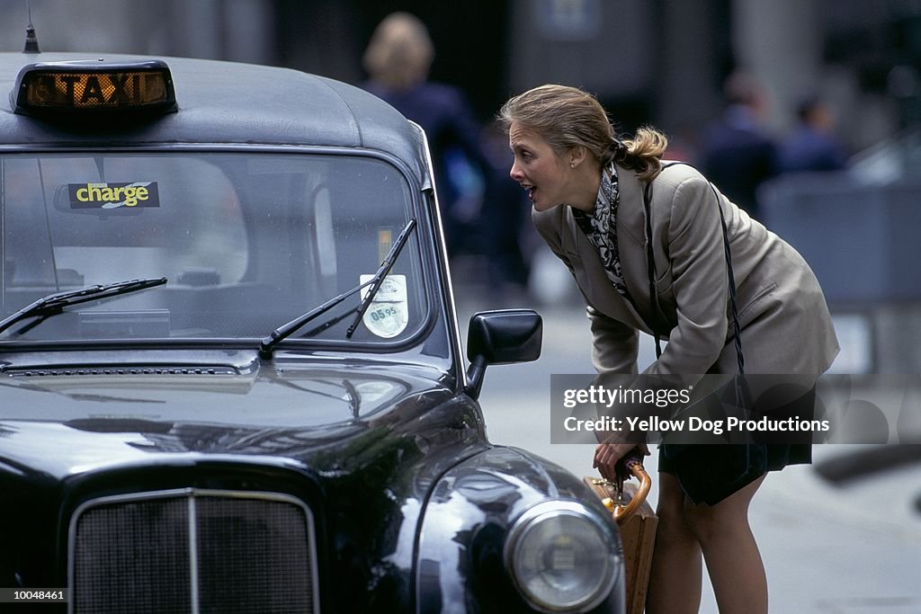 BUSINESSWOMAN HAILING A CAB IN LONDON