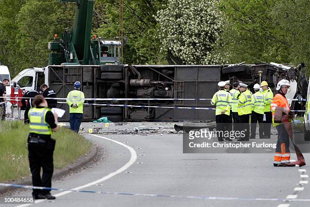 Police and emergency personnel stand by an overturned coach following a road crash on May 24, 2010 in Keswick, England. Three people were killed in...