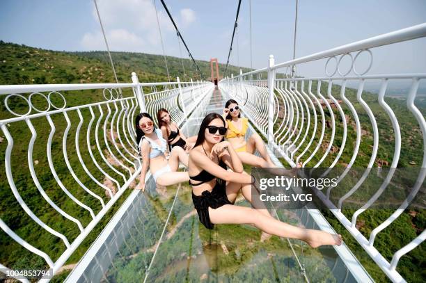 Girls pose on the 188-metre-long 5D Glass Suspension Bridge at Wan'anshan Grand Canyon on July 21, 2018 in Luoyang, Henan Province of China. The 5D...