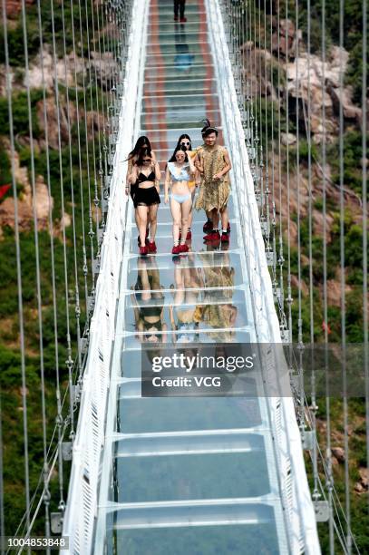 Girls pose on the 188-metre-long 5D Glass Suspension Bridge at Wan'anshan Grand Canyon on July 21, 2018 in Luoyang, Henan Province of China. The 5D...