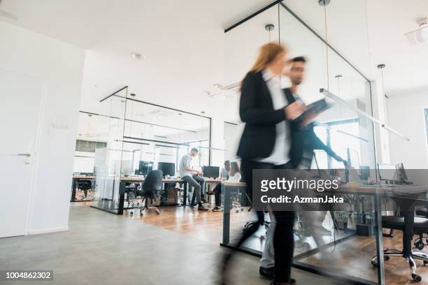 business colleagues walking and talking - place of work stock pictures, royalty-free photos & images