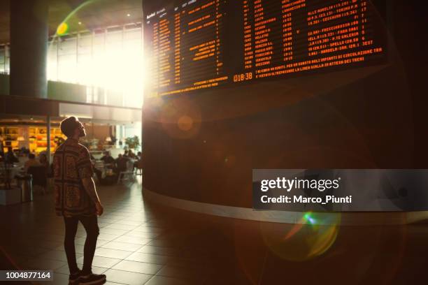 young men checking his train in time board - airport departure board stock pictures, royalty-free photos & images