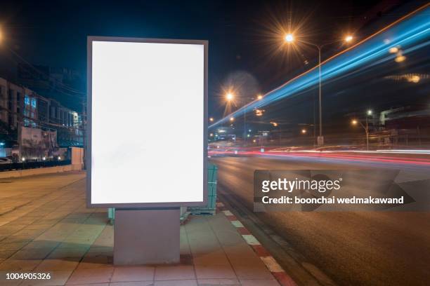 blank billboard on city street at night. outdoor advertising - bus sign photos et images de collection