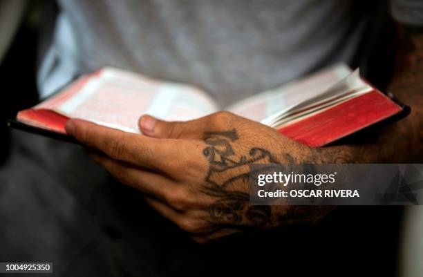 Former gang member holds a Bible at the prison of San Francisco Gotera, 161 km east of San Salvador on July 16, 2018. - Members of two of the world's...