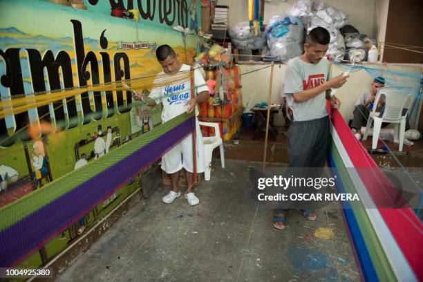 Former gang members weave a hammock at the prison of San Francisco Gotera, 161 km east of San Salvador on July 16, 2018. - Members of two of the...