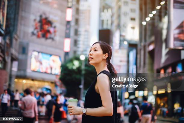 beautiful young asian woman holding coffee visiting and exploring in the busy downtown city street of hong kong - causeway bay stockfoto's en -beelden