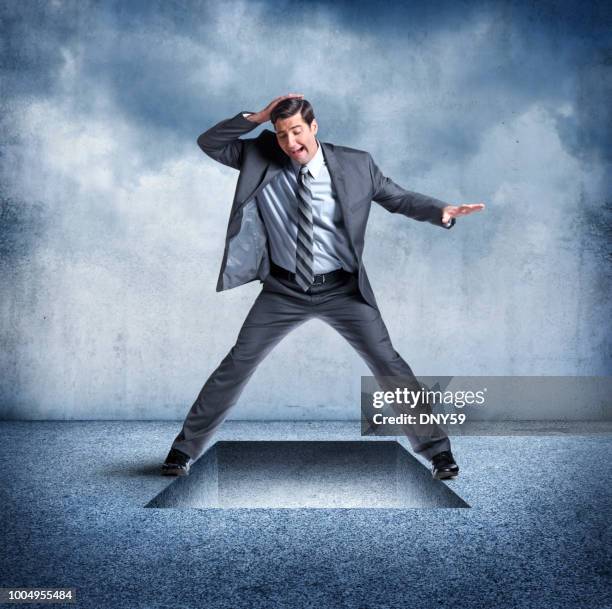 businessman straddles trap door opening - falling through trap door stock pictures, royalty-free photos & images