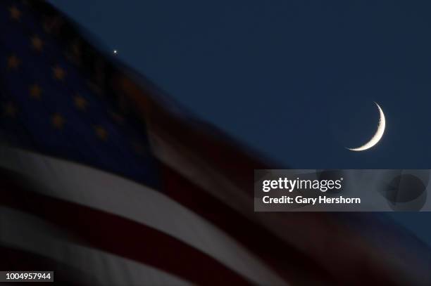 Crescent moon and the planet Venus set behind an American flag at sunset on July 15, 2018 in Bayonne, New Jersey.