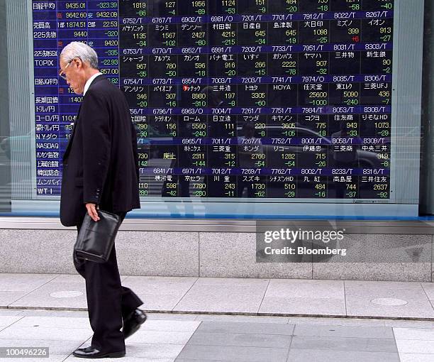 Man walks past an electronic stock board outside a securities firm in Tokyo, Japan, on Tuesday, May 25, 2010. Japanese stocks fell, dragging the...