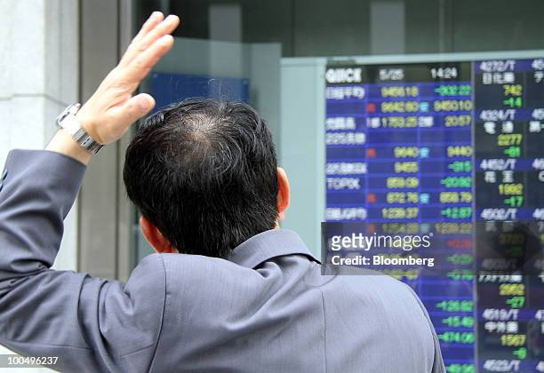 Man looks at an electronic stock board outside a securities firm in Tokyo, Japan, on Tuesday, May 25, 2010. Japanese stocks fell, dragging the Nikkei...