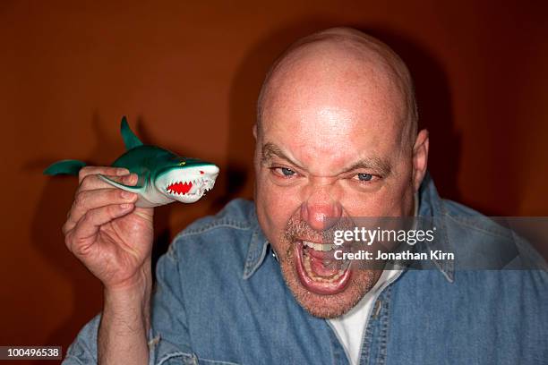 a shouting man holds a plastic shark.  - angry bald screaming man fotografías e imágenes de stock