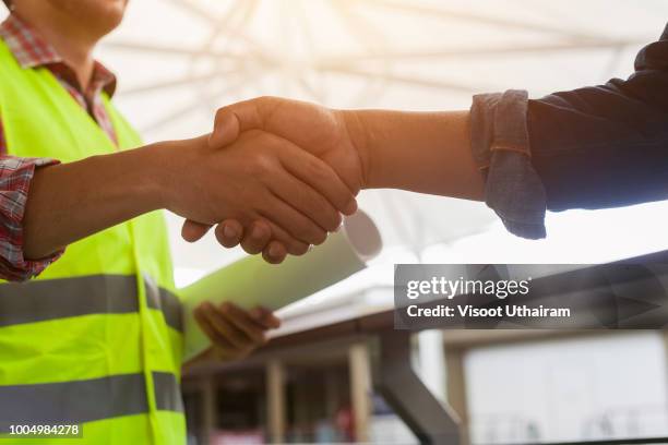 construction workers in protective helmets and vests are shaking hands - shaking bildbanksfoton och bilder