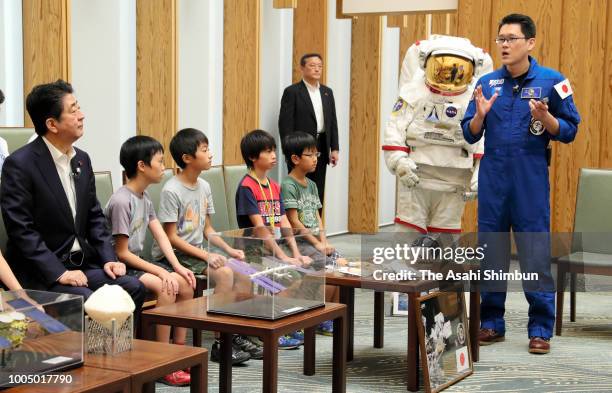 Japan Aerospace Exploration Agency astronaut Norishige Kanai explains to Prime Minister Shinzo Abe and children during their meeting at his official...