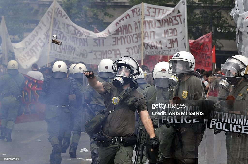 A Greek riot pliceman throws a tear gas