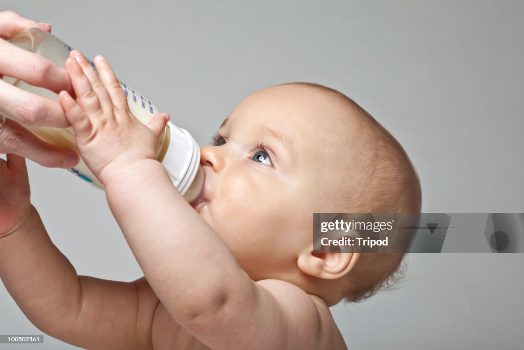 Woman giving baby boy (6-9 months) bottle