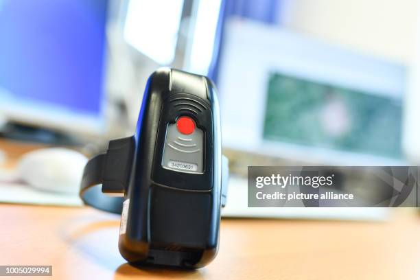 July 2018, Weiterstadt, Germany: A anklet lies in front of a workstation with several computer screens in the prison in the rooms of the Joint...