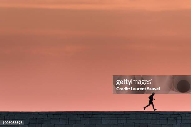 silhouette of a running man at sunset under a beautiful pink orange sky - laurent sauvel photos et images de collection
