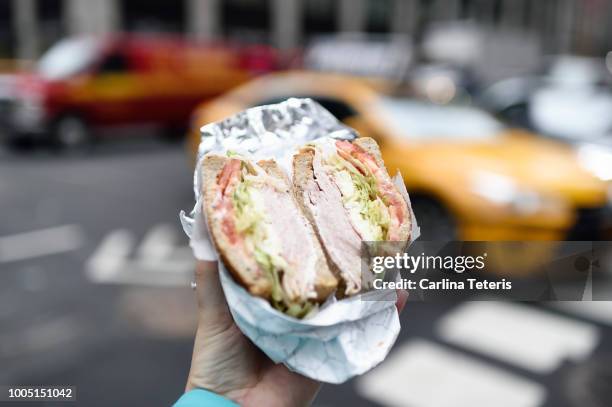 hand holding out a deli sandwich in new york city - new york food stockfoto's en -beelden