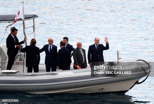 Prince Albert II of Monaco waves from a boat with dignitaries including Archbishop of Monaco Bernard Barsi during a presentation on the...