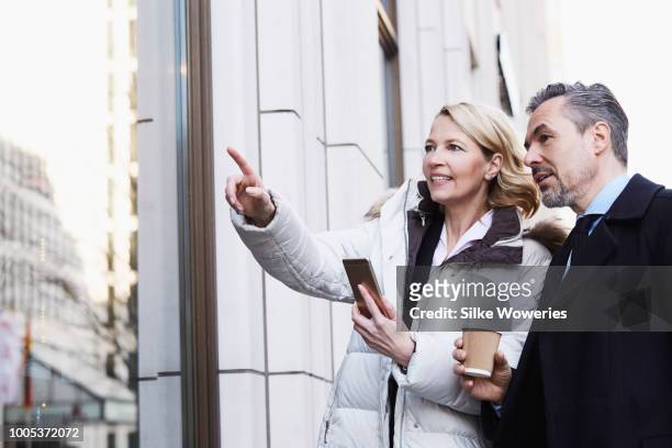 happy wealthy couple walking the city streets in winter - mature couple winter outdoors stockfoto's en -beelden