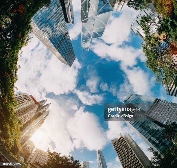 low angle view of contemporary corporate skyscrapers and urban park in financial district of hong kong on a fresh bright morning - commercial buildings hong kong morning stock pictures, royalty-free photos & images