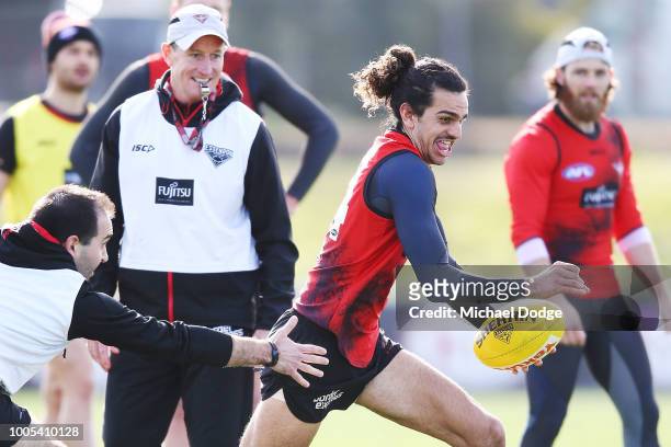 Jake Long of the Bombers runs with the ball past Bombers head coach John Worsfold during an Essendon Bombers AFL training session at The Hangar on...