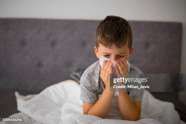 ziek jongetje reiniging van de neus in bed - respiratory infection stockfoto's en -beelden