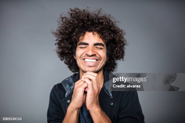 smiling young man praying with eyes closed - man smiling eyes closed stock pictures, royalty-free photos & images