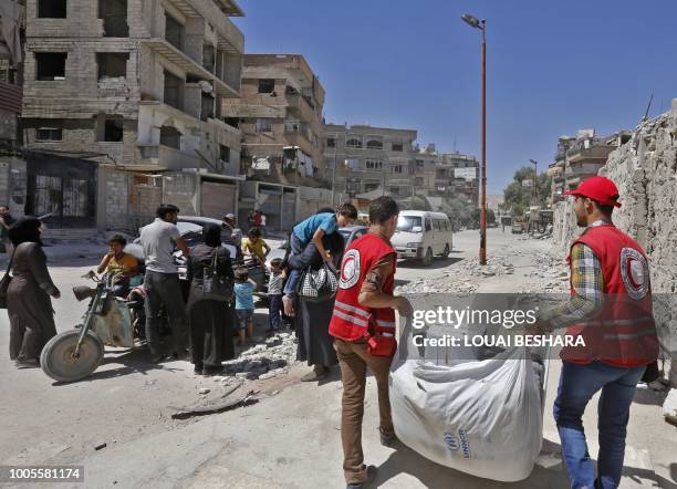 Members of the Syrian Arab Red Crescent distribute humanitarian aid to residents of the town of Douma as part of a humanitarian assistance provided...