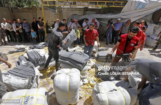 Members of the Syrian Arab Red Crescent distribute humanitarian aid to residents of the town of Douma as part of a humanitarian assistance provided...