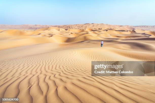 lonely man on sand dune in the desert of abu dhabi - arabian peninsula fotografías e imágenes de stock