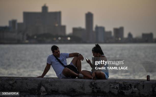 Couple rests at the Malecon in Havana on July 12, 2018. - Havana, object of desire of historians and tourists, will celebrate its 500th anniversary...