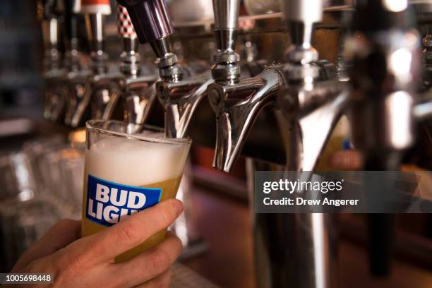 In this photo illustration, a bartender pours a Bud Light from a tap, July 26, 2018 in New York City. Anheuser-Busch InBev, the brewer behind...