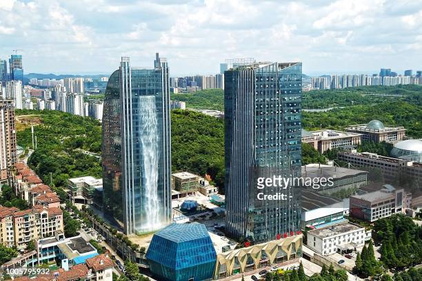 This photo taken on July 20, 2018 shows a 108-meter-high artificial waterfall on the facade of the Liebian International Building in Guiyang in...