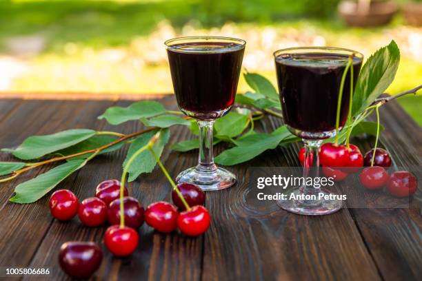 cherry liqueur and fresh cherries on a wooden background - likör stock-fotos und bilder