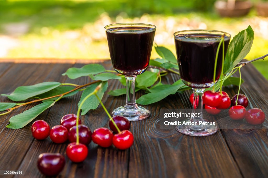 Cherry liqueur and fresh cherries on a wooden background
