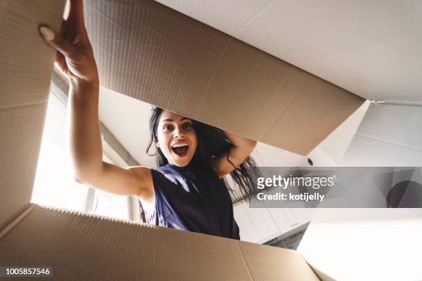 donna sorridente che apre una scatola di cartone - regalo foto e immagini stock
