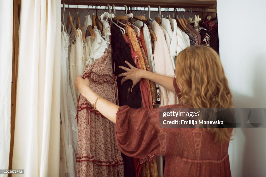 Young woman standing in front of her closet choosing something to wear
