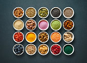 Various colorful superfoods in bowls on dark background