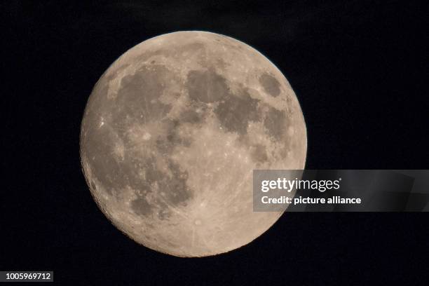 July 2018, Germany, Cologne: The full moon shines in the sky. The total lunar eclipse on late Friday evening will probably be well visible in North...