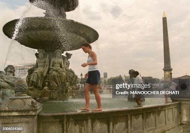 Des touristes cherchent un peu de fraîcheur dans la fontaine de la place de la Concorde, le 01 août à Paris, alors que les températures supérieures à...