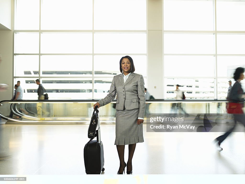 Mature businesswoman with luggage standing in airport corridor