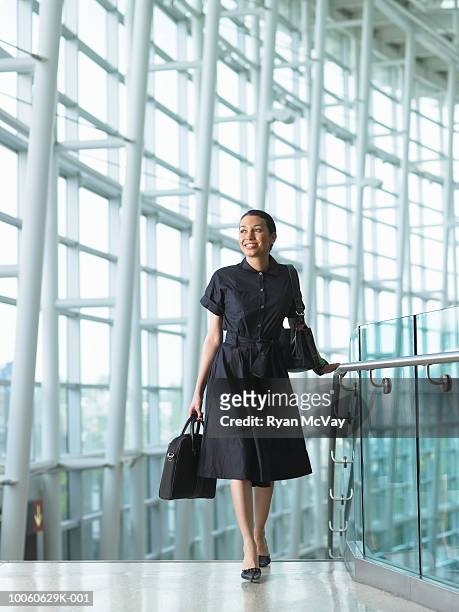young businesswoman walking up stairway in airport, smiling - airport stairs stock pictures, royalty-free photos & images