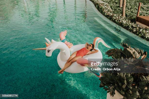 carefree woman on inflatable unicorn - unicorn stock pictures, royalty-free photos & images