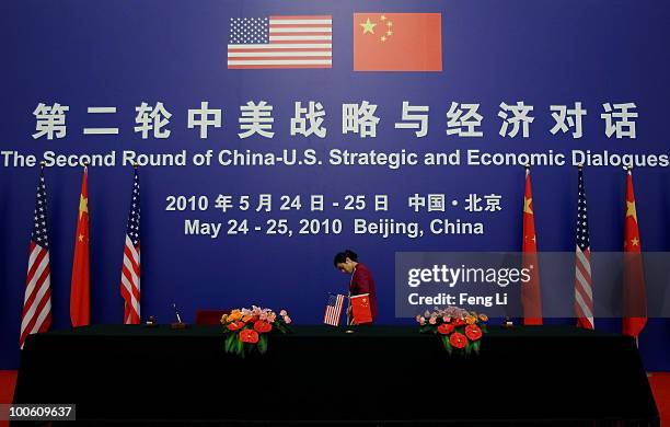 Waitress cleans the carpet in front of American and Chinese flags ahead of a press conference for the China-U.S. Strategic and Economic Dialogue at...