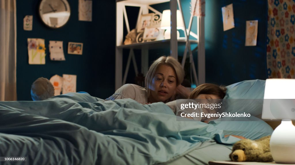 Woman telling story to girl in bed